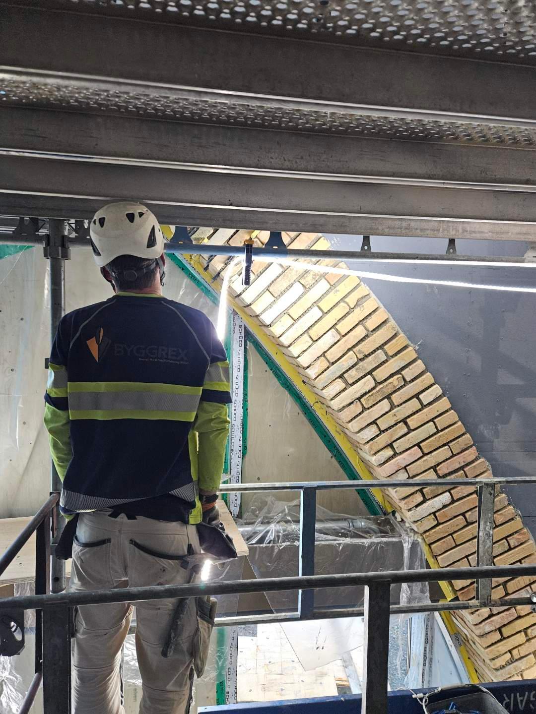 Byggarbetare framför fasad med återbrukat tegel