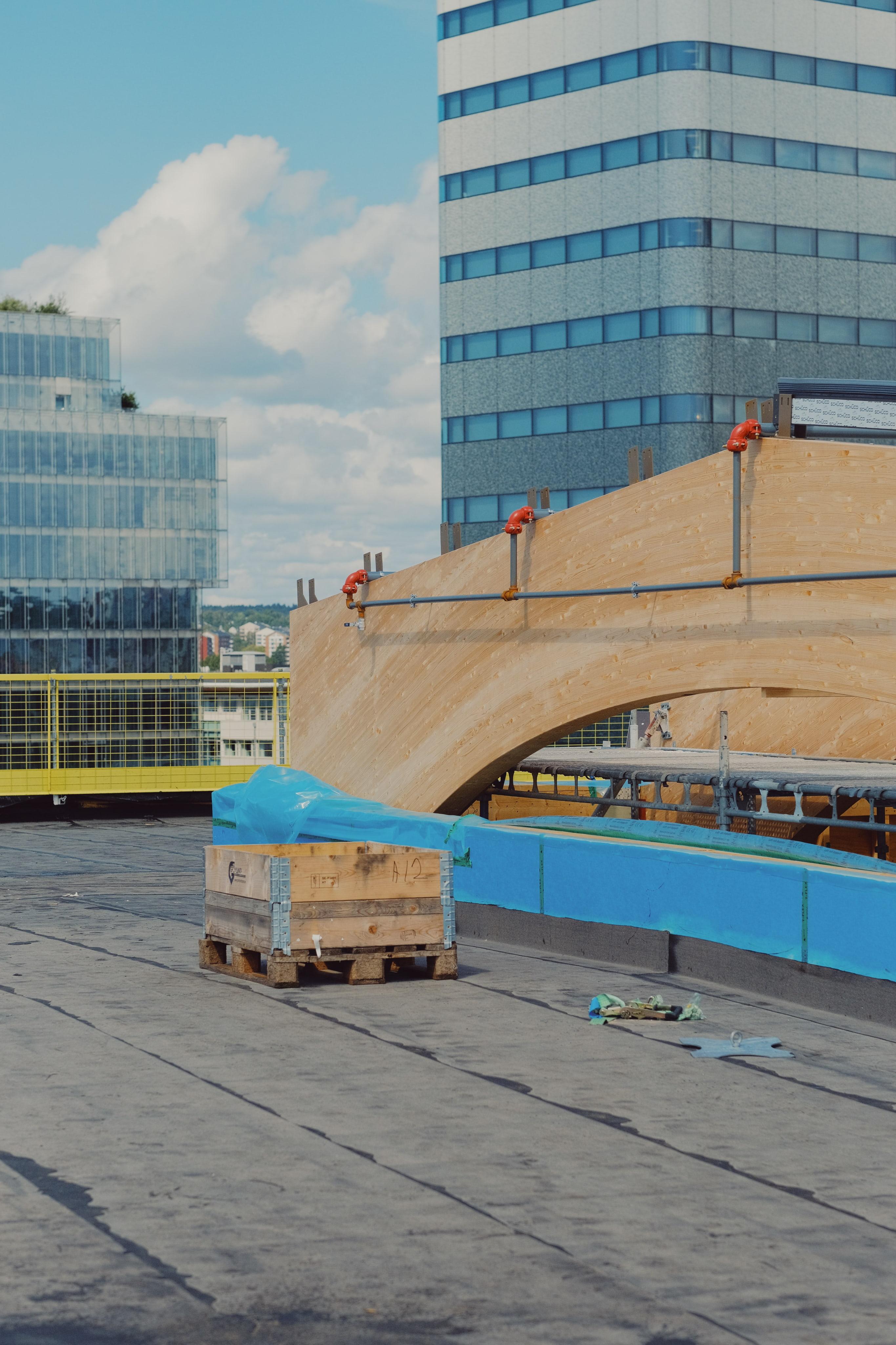 Byggarbetsplats med träbågar under montering på taket av Göteborg Grand Central, med moderna kontorsbyggnader i bakgrunden